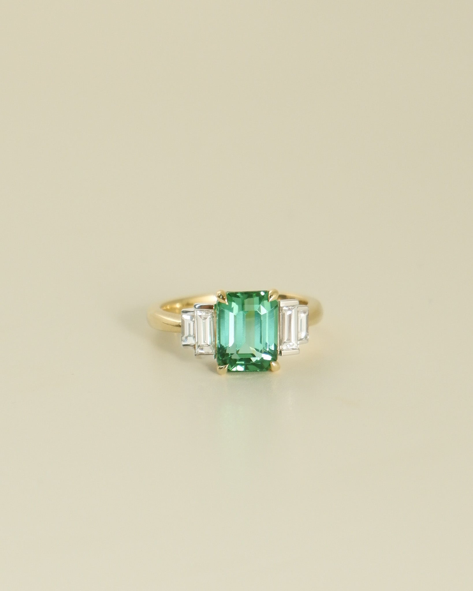A.G tourmaline and diamond step style ring on beige background.