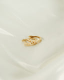 A.G Designer Jeweller signature bezel set diamond huggie earrings in yellow gold on white satin sheet.