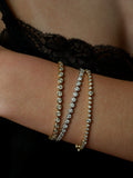 Close up of wrist wearing three diamond tennis bracelets in yellow gold and white gold.