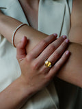 Women's hand holding arm. A.G custom trilogy with Sri Lankan yellow sapphire and diamonds ring is on finger.