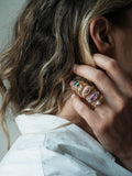 Close up of woman's hand featuring 5 different signet rings on her ring finger.