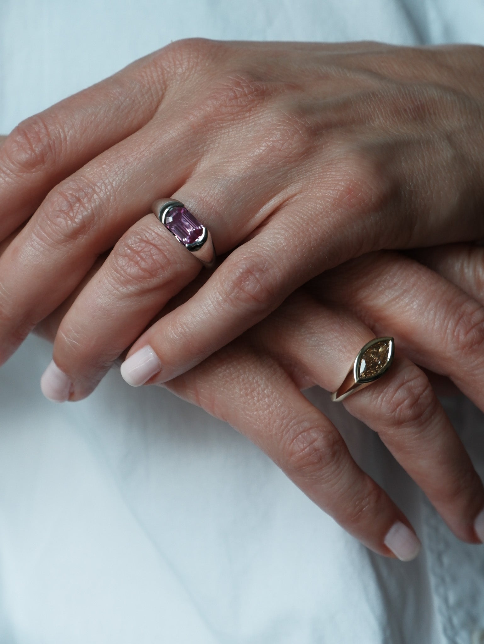 Close up of hands, one hand has A.G Designer Jeweller custom designed signet ring featuring a 1.56ct marquise cut champagne diamond in yellow gold on it.