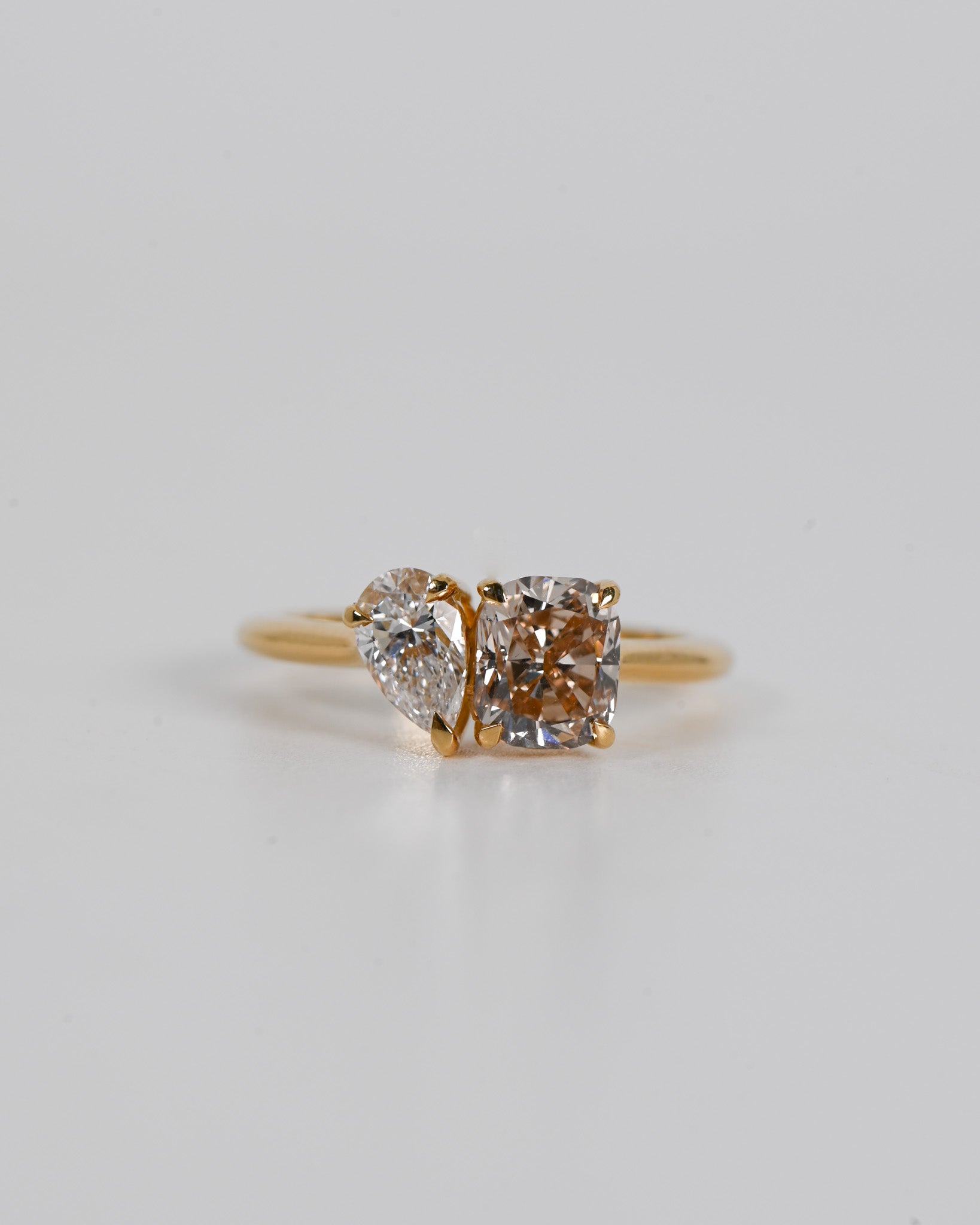 A.G 1.56ct cushion cut champagne diamond and 0.52ct pear cut diamond ring with white background.