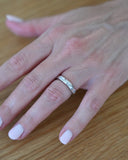 Close up of hand wearing silver A.G Designer Jeweller signature custom designed hammer set oval cut diamond wedding ring.