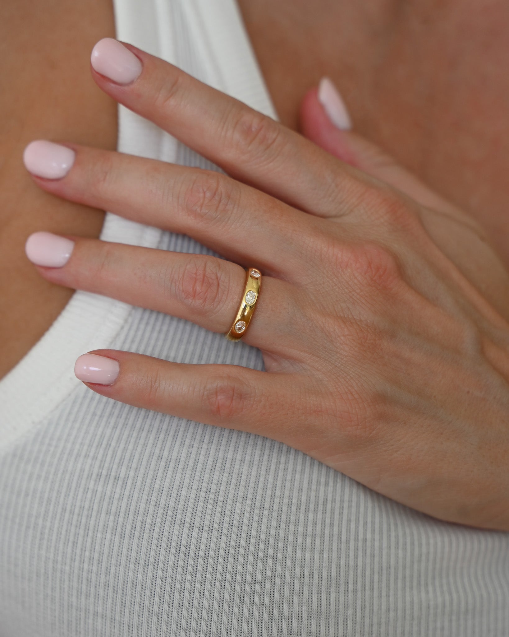 Close up of hand with Gold A.G Designer Jeweller signature custom designed hammer set oval cut diamond wedding ring.