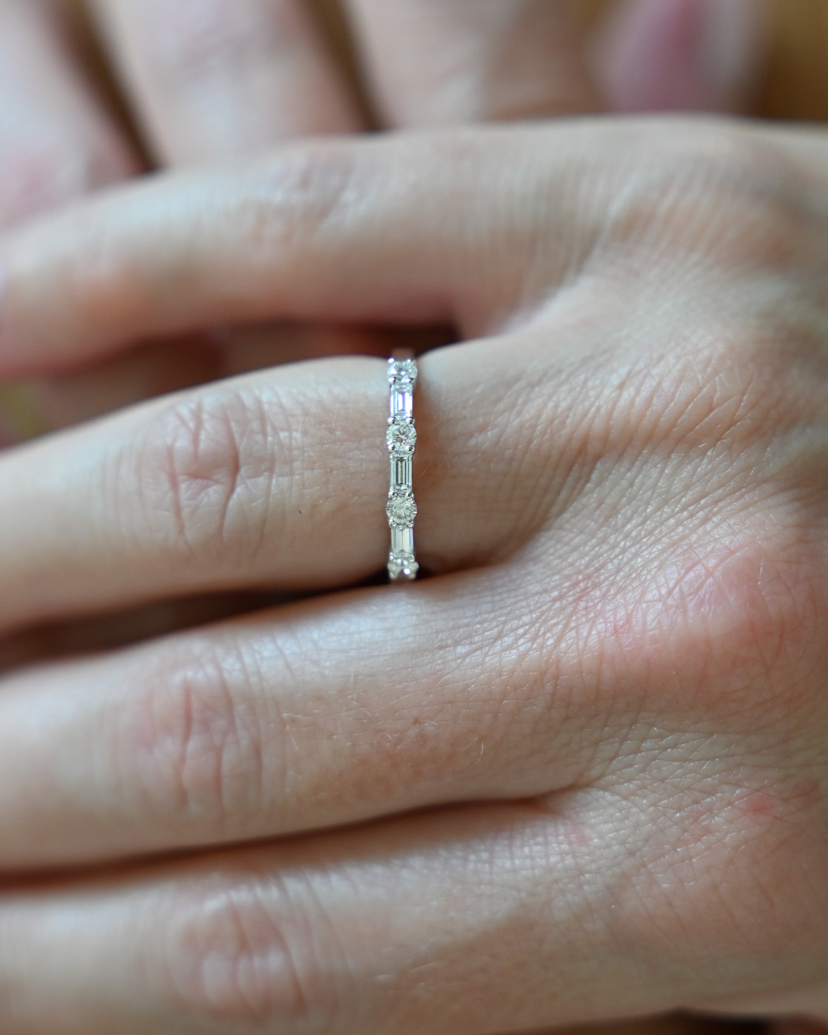 Close up of hand with A.G alternating diamond wedding band on finger