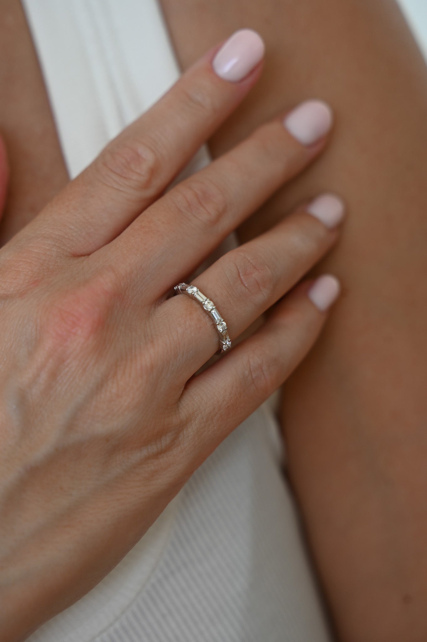 Hand with A.G alternating diamond wedding band on finger.