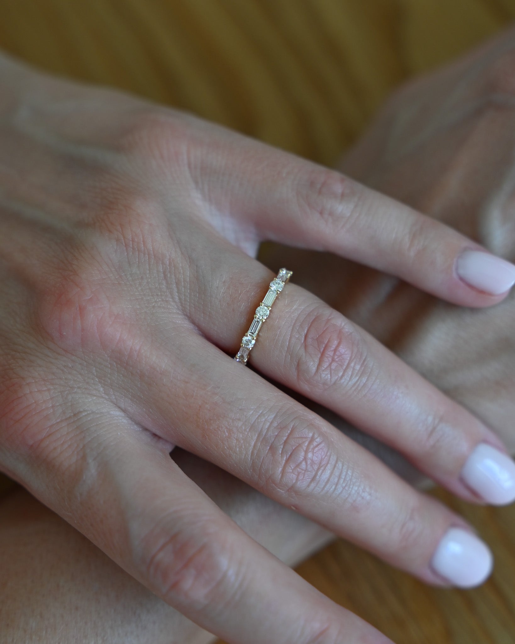 Close up of hand with A.G alternating diamond wedding band in gold on finger