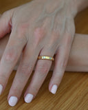 Close up of hand wearing A.G hammer set emerald cut wedding band in Gold.