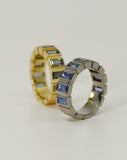 Custom made blue sapphire bezel set ring in white gold next to custom made green sapphire bezel set ring in yellow gold.