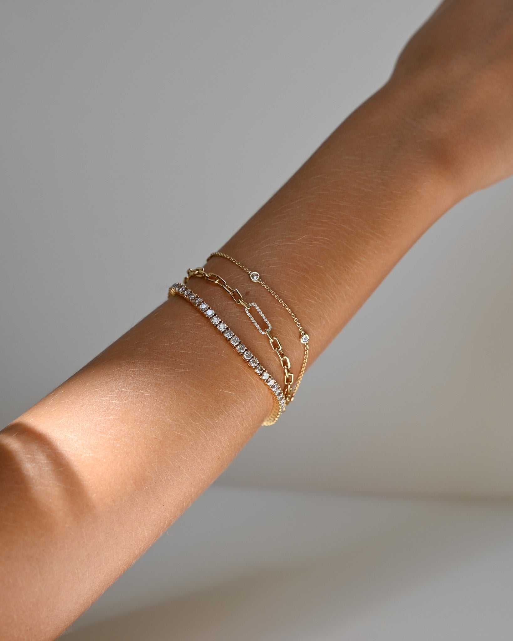 Close up of wrist wearing three A.G Designer Jeweller custom made yellow gold bracelets.