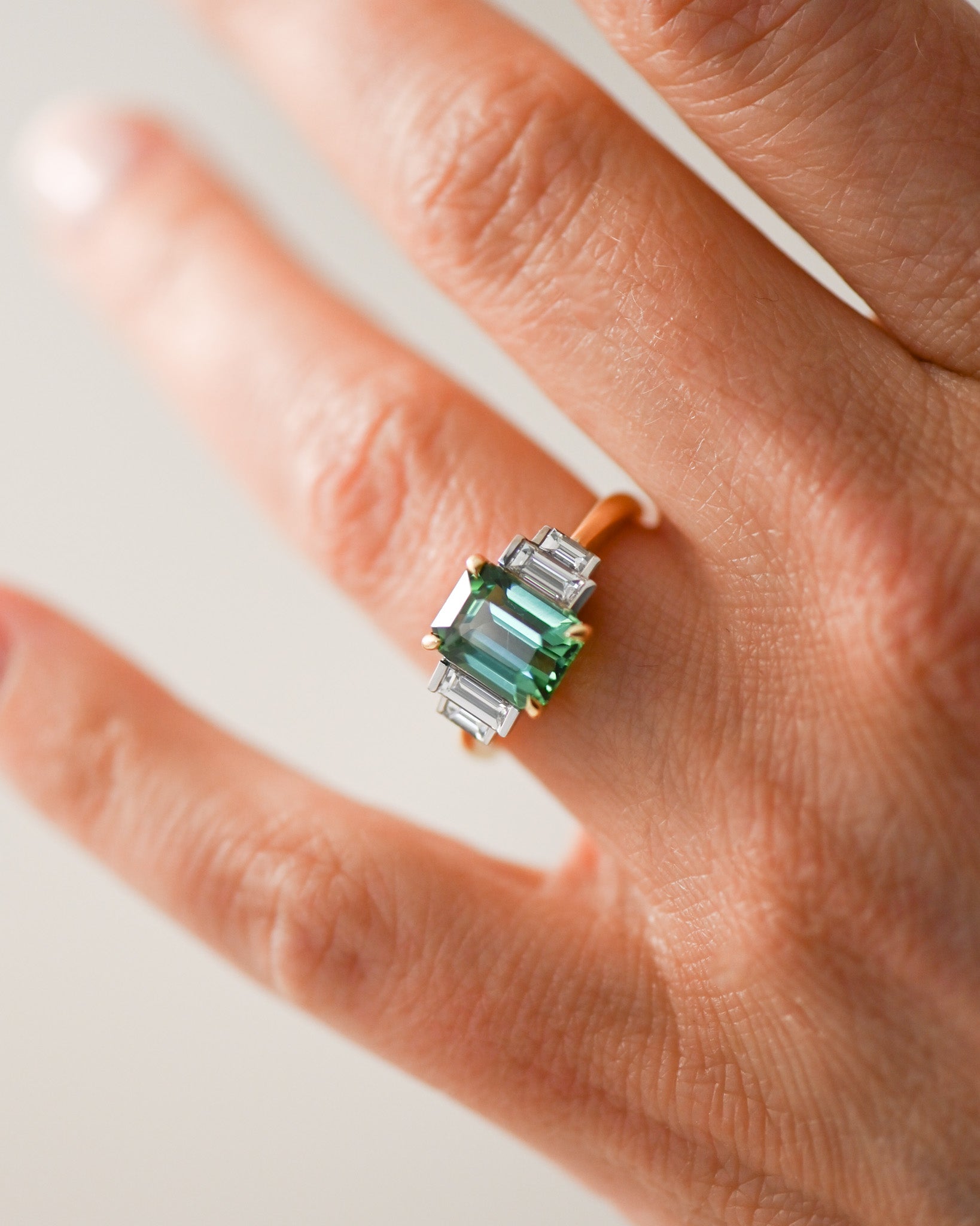Close up of A.G tourmaline and diamond step style ring on finger.