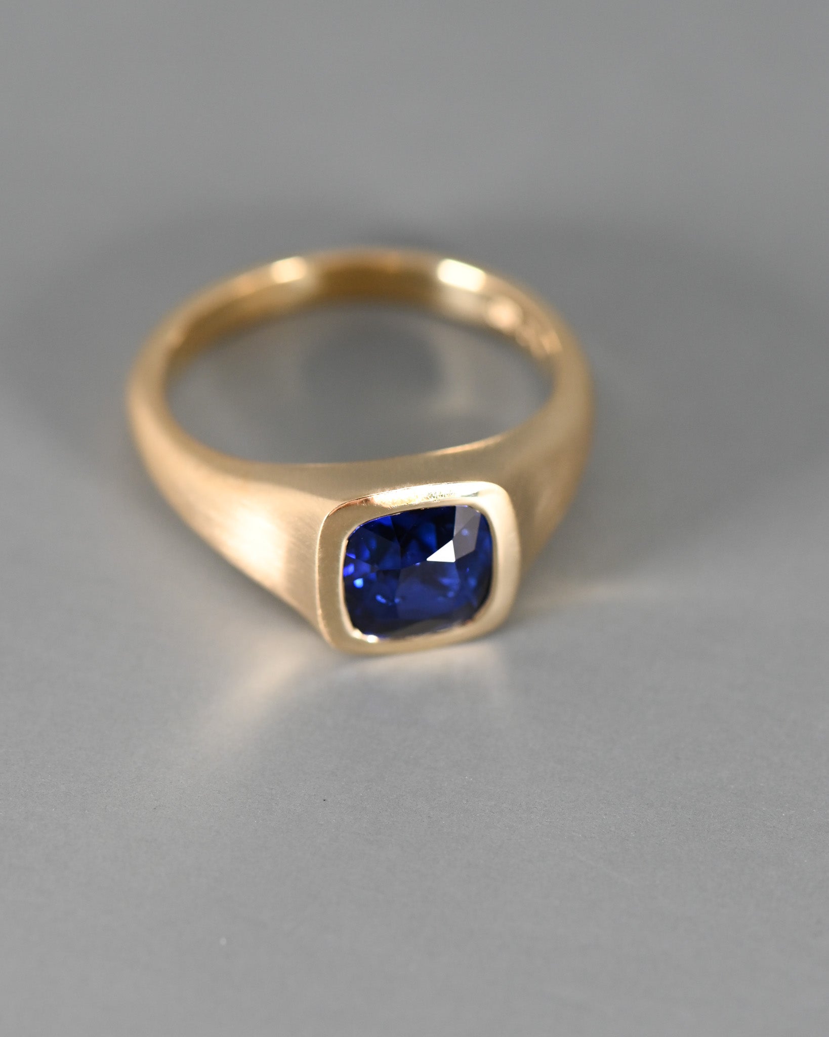 Top view of A.G Designer Jeweller custom designed men's signet ring with royal blue sapphire in yellow gold.