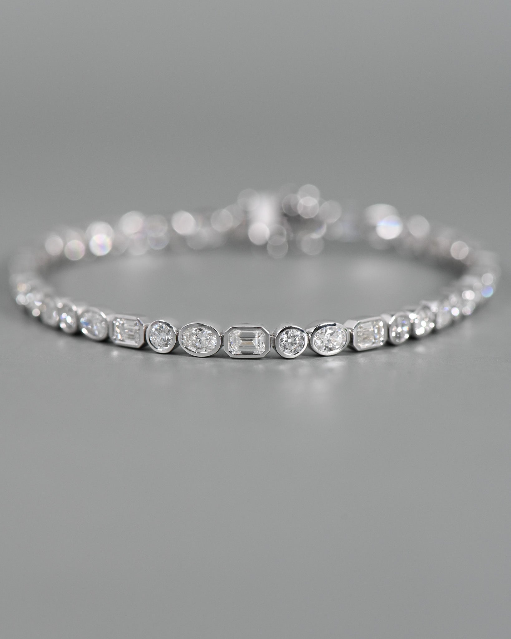 Close up view of A.G Designer Jeweller custom made alternating tri diamond tennis bracelet in white gold.