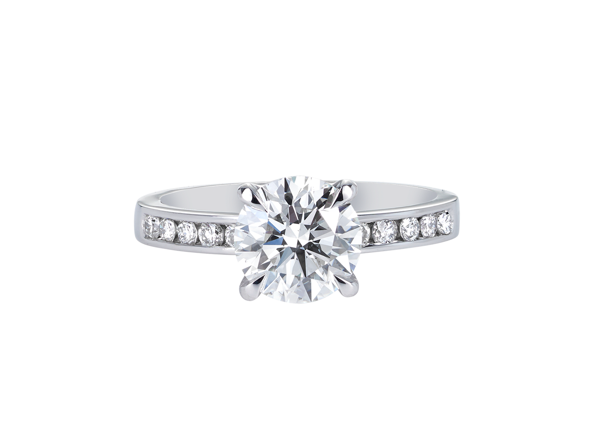 A.G round brilliant cut diamond four claw setting with channel set diamond band.